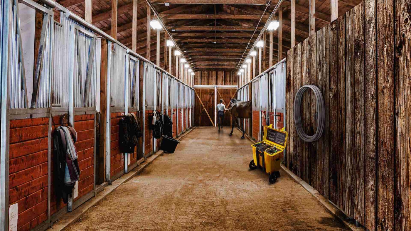 A Pulse equine PEMF unit in a stable aisle as a horse is led through the barn
